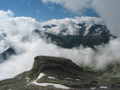 Das Petersköpfl mit breitem Gipfelplateau vor Wolken.